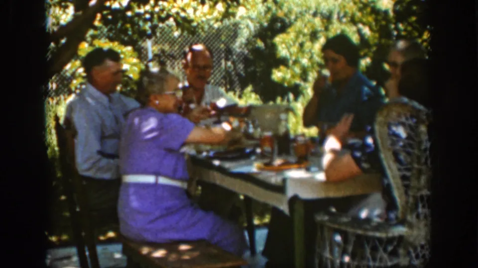 Auburn, California family gathering frame showing adults at a garden table, including a woman in purple reaching forward.