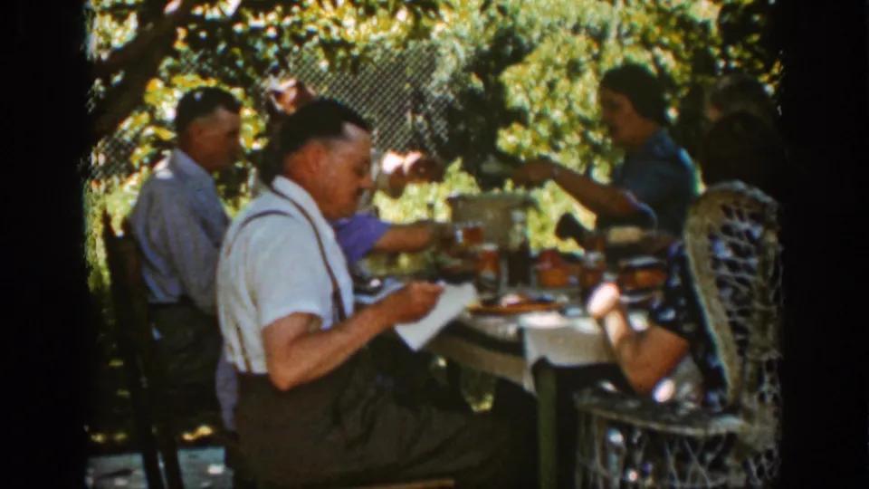 Auburn, California 1939 frame showing a man at a backyard picnic table handling a napkin beside seated relatives.