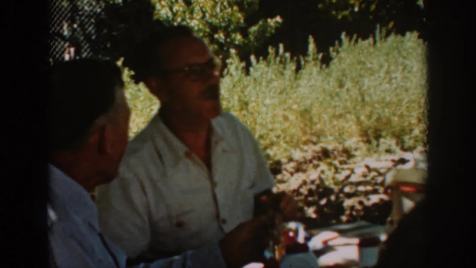 The Auburn, California home-movie frame shows the man in glasses mid-conversation with foliage behind him.