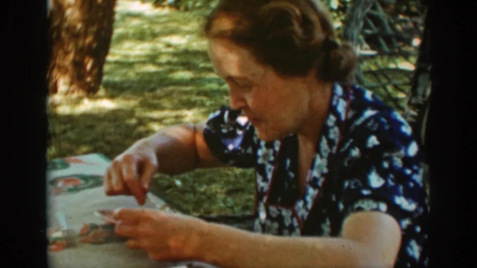 Older woman in a blue floral dress looks down and works with a spoon or food at an outdoor table in Auburn, California.