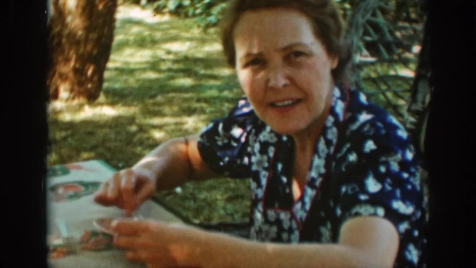 Older woman faces the camera while seated at a shaded outdoor table in 1939 Auburn, California footage.