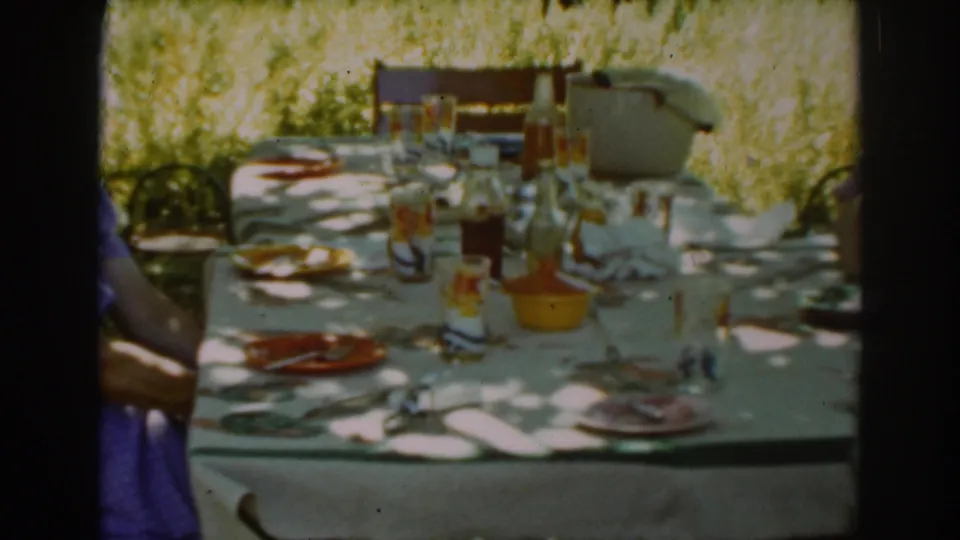 Auburn, California picnic scene from 1939 showing a long table set with dishes and bottles, with a person partly visible nearby.
