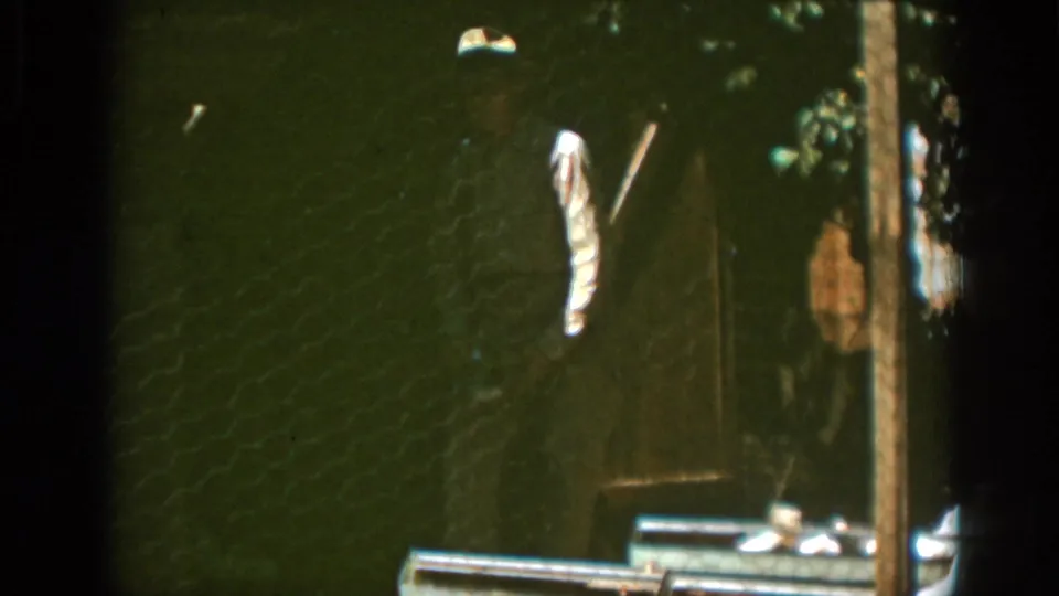 The final Auburn, California frame holds on the chicken wire, wooden troughs, doorway, and a few remaining chickens after the man moves out of view.