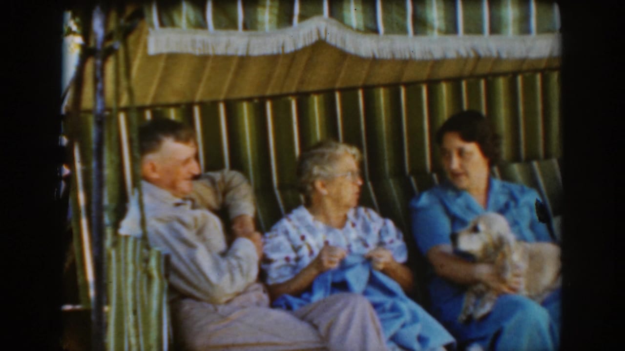 An older man and two women sit close together as the woman on the right holds a small dog.