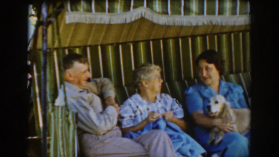 A candid 1939 Auburn home-movie frame shows the older man smiling while the two women look toward each other beside the small dog.