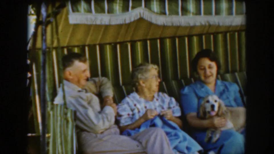 The final frame shows the Auburn, California seated group in soft 8mm color, with the dog facing camera and the adults relaxed together.