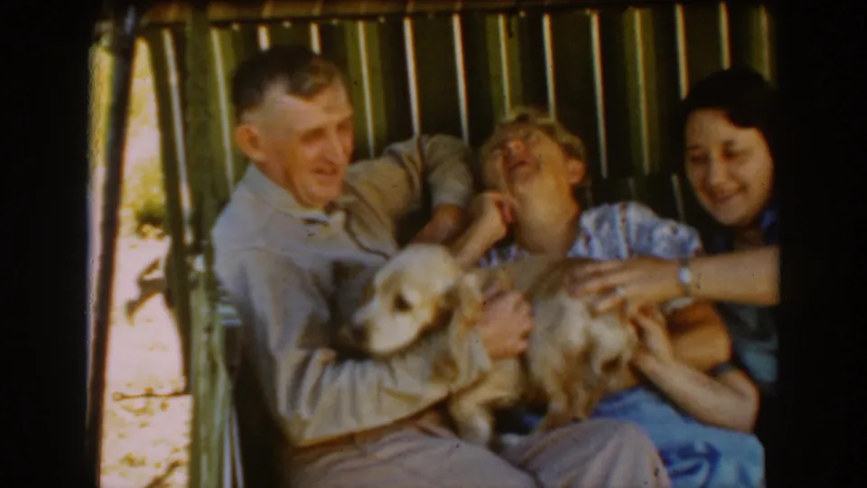 Three adults in the 1939 Auburn porch scene laugh and react while the dog stretches across their seated group.