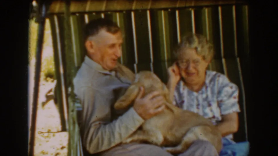 The man holds the dog close as the older woman adjusts her glasses in this Auburn 1939 home-movie frame.