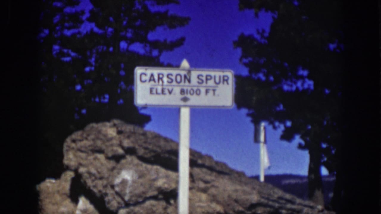 Carson Spur elevation sign beside rocks and dark pine trees.