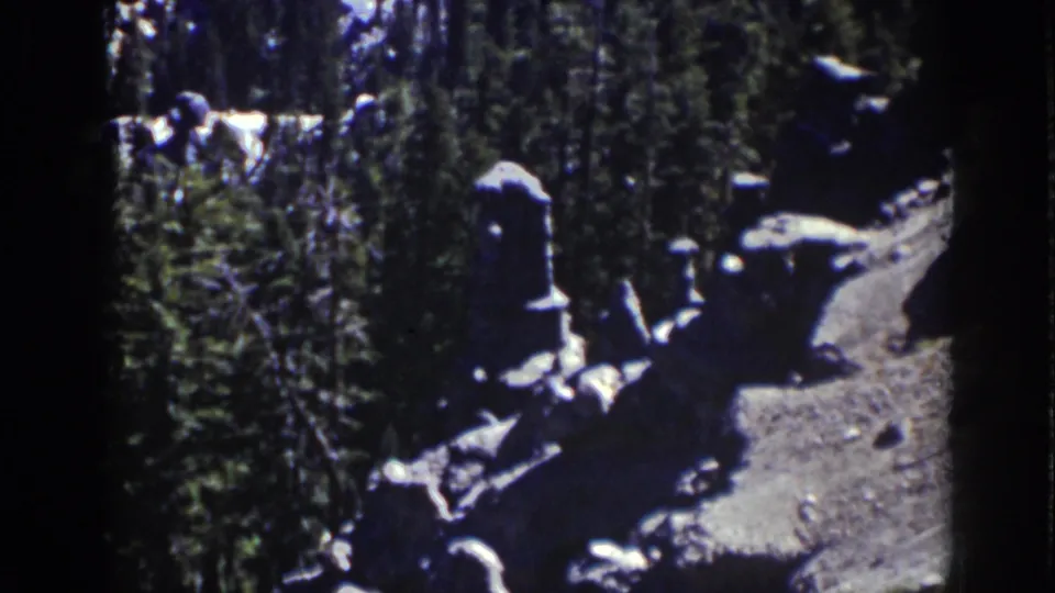 Lake Tahoe 8mm frame from 1939 showing grey boulders, dark evergreens, sunlit rock, and steep shadowed terrain.