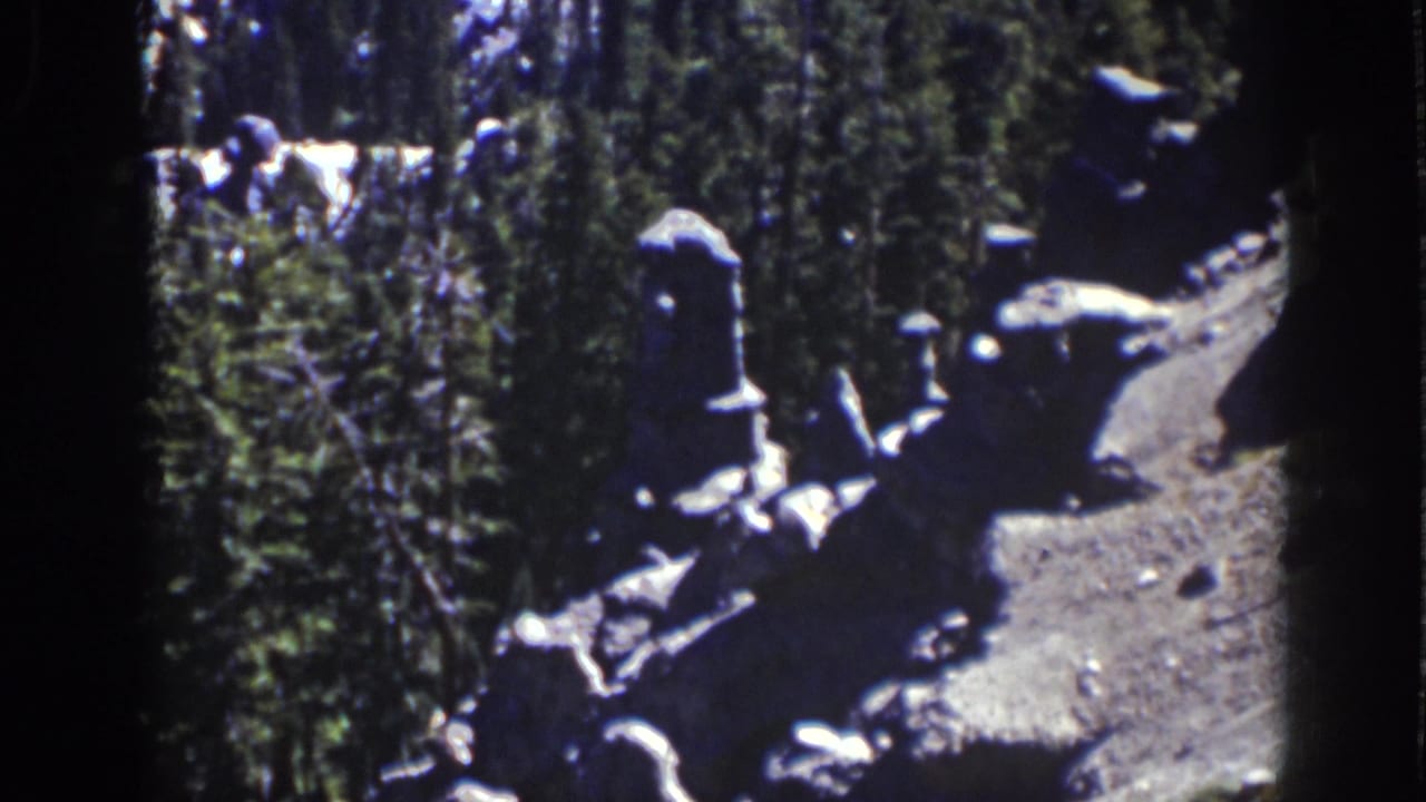 Rock formations beside evergreen trees on a mountain path.