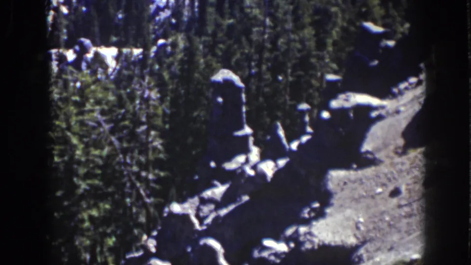 1939 Lake Tahoe home-movie frame showing pale rock formations beside dense evergreens along a rough mountain path.