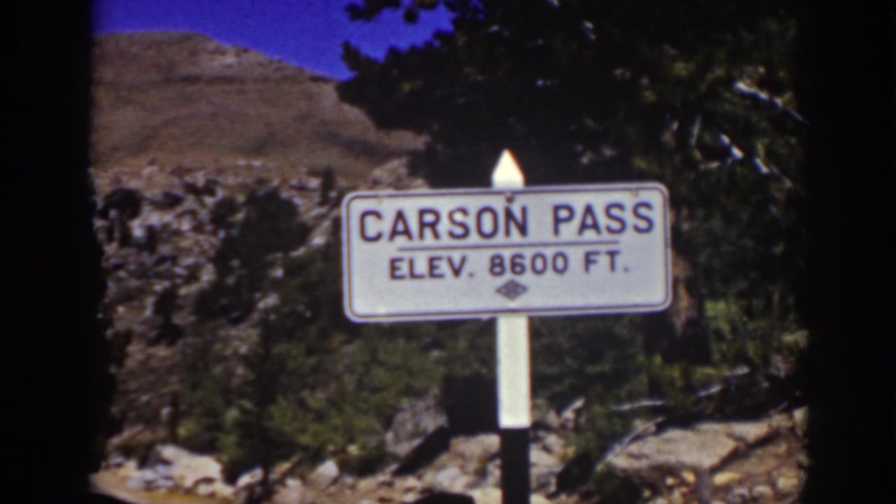 Carson Pass elevation sign beside rocky terrain and evergreen trees.