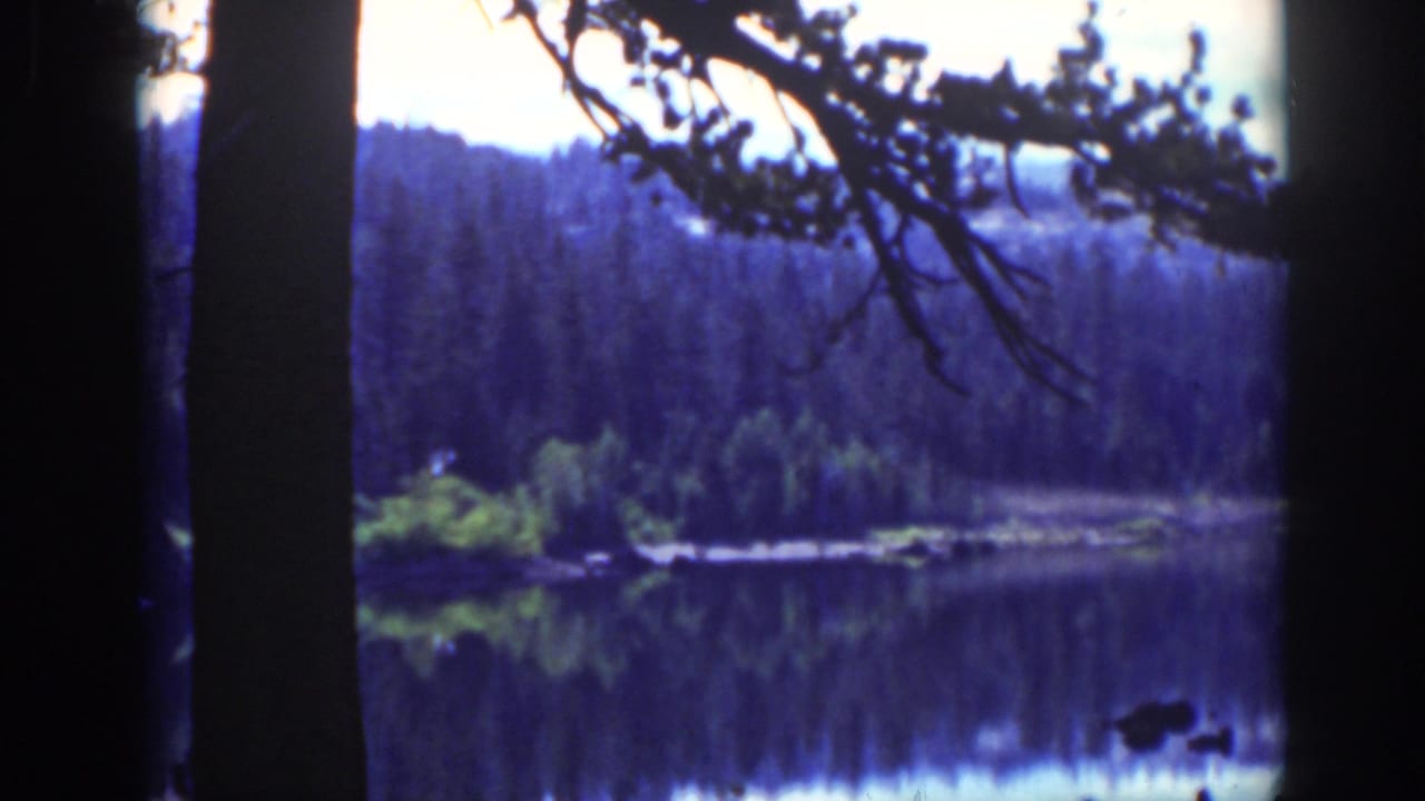 Vintage 8mm Lake Tahoe frame showing calm water, forested shore, and blue-purple early color cast.