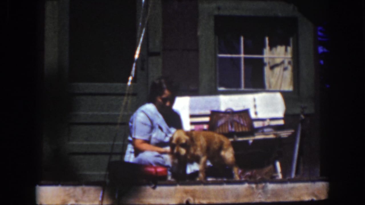 A Lake Tahoe 1939 home-movie frame shows the woman leaning toward the dog as it stands on the porch step.