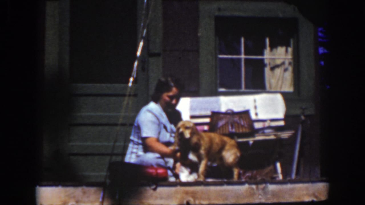 A 1939 Lake Tahoe frame shows the woman seated close to the dog, with a cloth and porch window visible behind them.