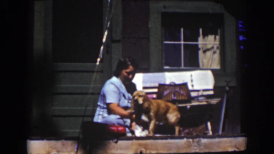 A 1939 Lake Tahoe frame shows the woman seated close to the dog, with a cloth and porch window visible behind them.