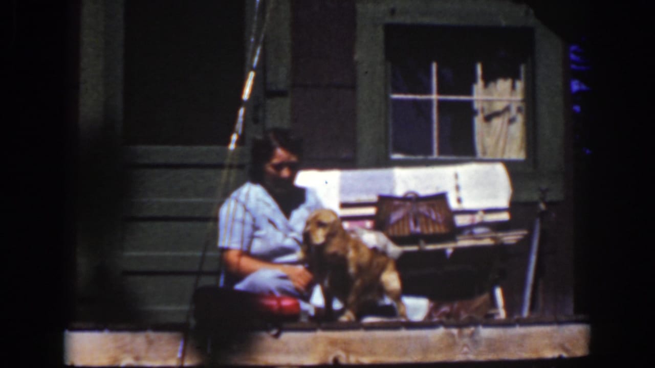 The 1939 Lake Tahoe home-movie frame shows the woman turned toward the dog as it stands near the porch wall and window.