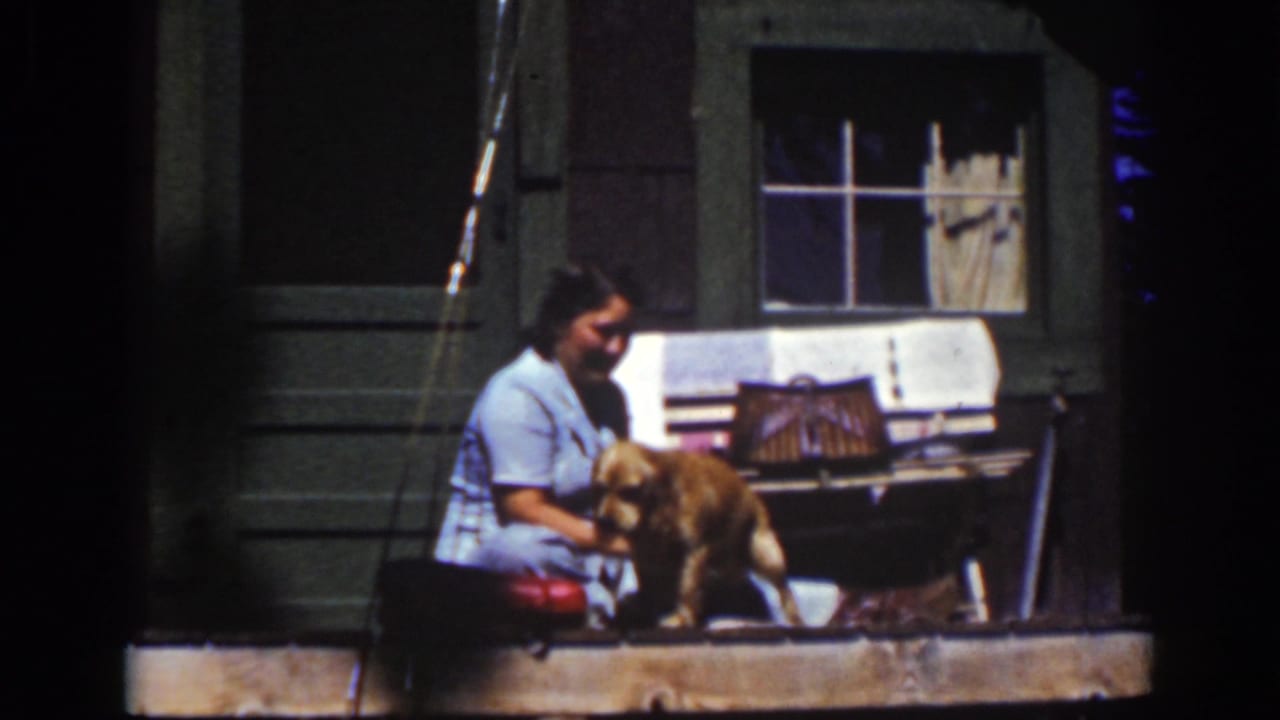 A woman sits on a porch step at Lake Tahoe in 1939 while the golden-colored dog stands partly in front of her.