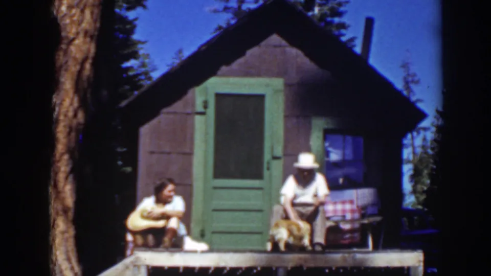 1939 Lake Tahoe frame of a couple resting on a rustic porch, with a golden dog beside the seated man.