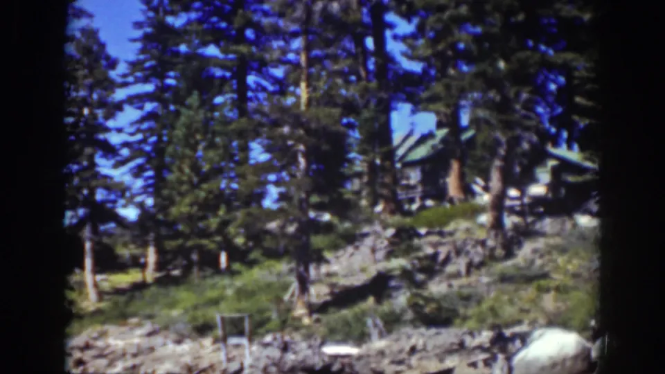 Lake Tahoe cabin exterior partly hidden by pines on a rocky hillside, from supplied 1939 home-movie footage.