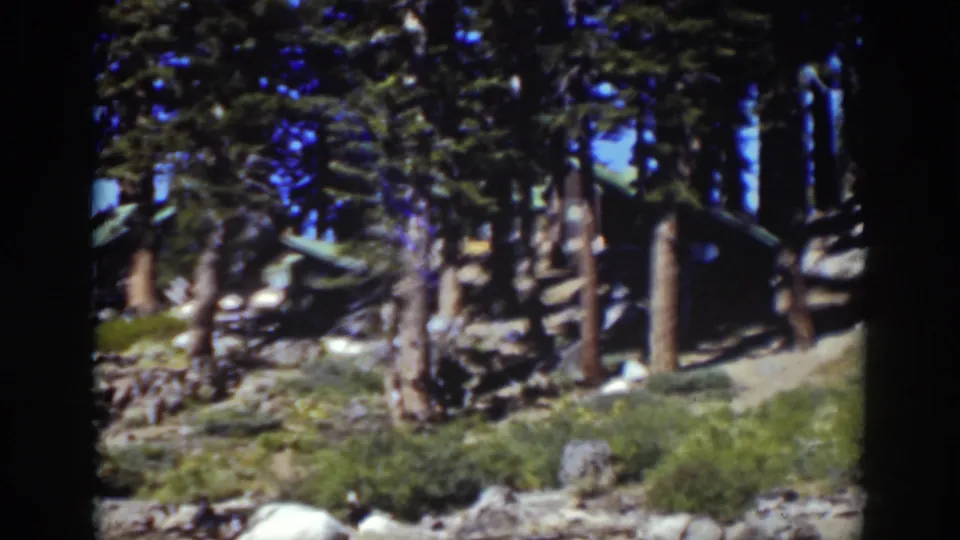 Lake Tahoe home-movie frame showing a cabin partially screened by pines on a rocky hillside in 1939 footage.