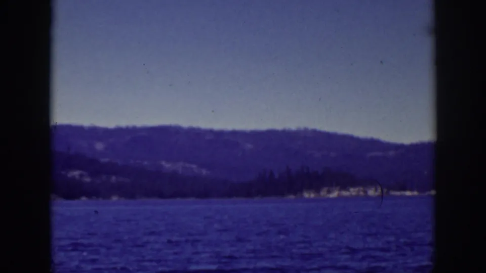 1939 Lake Tahoe home-movie view of rippled blue water, low shoreline trees, and layered hills in the distance.