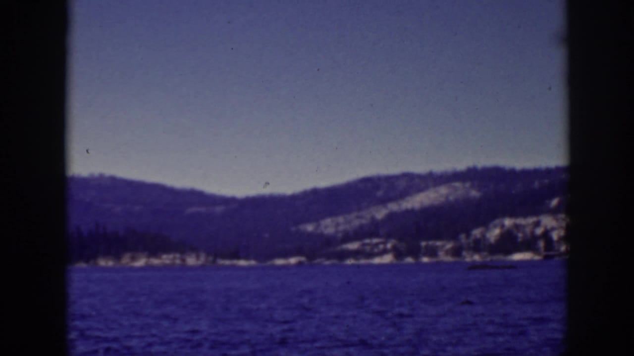 Lake Tahoe landscape frame with open water, distant snow-covered hills, pale sky, and prominent 8mm frame divisions.