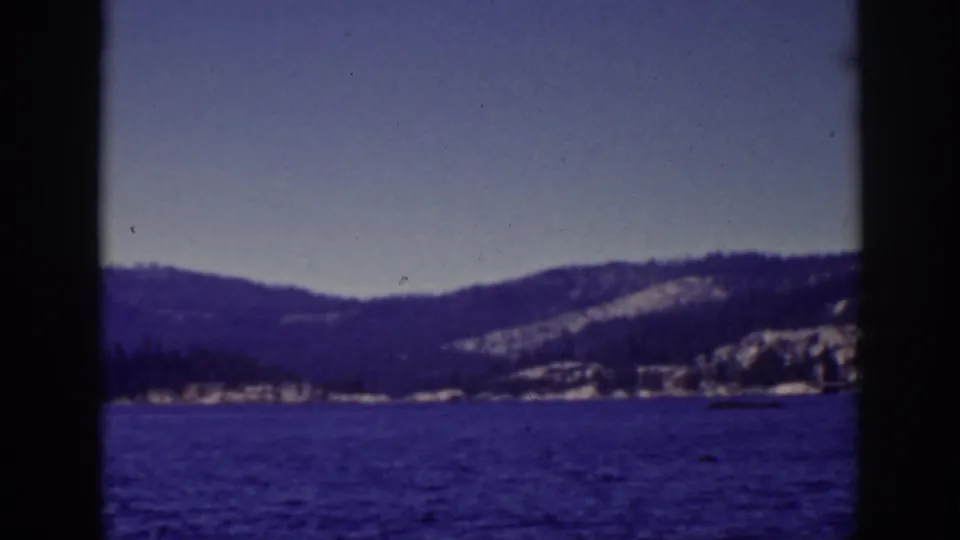 Lake Tahoe landscape frame with open water, distant snow-covered hills, pale sky, and prominent 8mm frame divisions.
