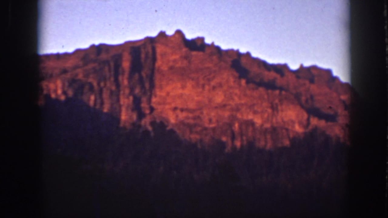 Lake Tahoe mountain ridge in 1939 8mm footage, with red sunrise light and silhouetted trees below.