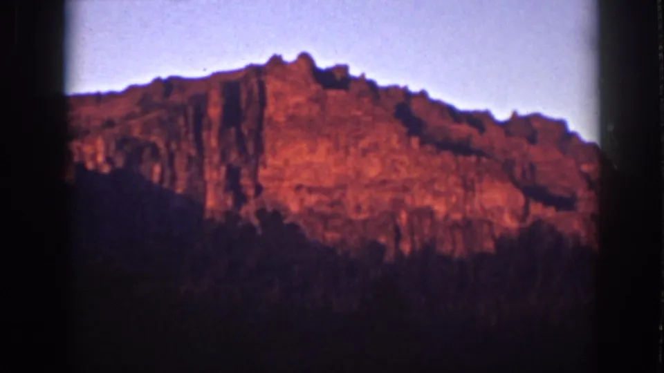 Vintage Lake Tahoe sunrise frame with textured red cliffs, soft sky, and dark forested foreground.