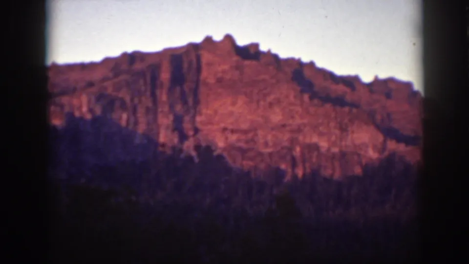 Final 1939 Lake Tahoe 8mm frame with a rocky formation, dark forest, pale sky, and visible film borders.
