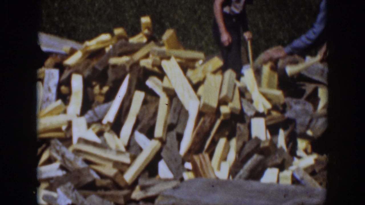 Large pile of split firewood with a partially visible person at the right edge.