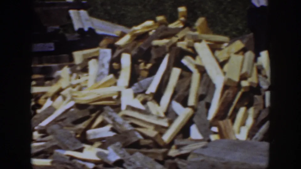 A close 1939 Lake Tahoe frame centers on a large pile of split firewood, with only small traces of the surrounding wooded setting visible.