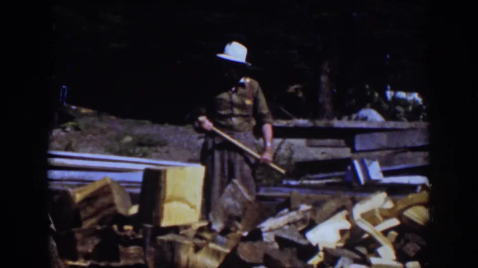 In the 1939 Lake Tahoe footage, a woman in a brimmed hat stands near the firewood pile holding an axe or similar tool.
