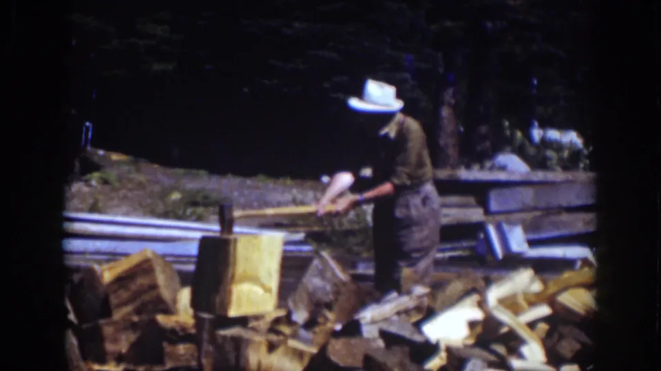 At Lake Tahoe in 1939, the man leans over a chopping block with an axe, surrounded by split logs and a wooded background.