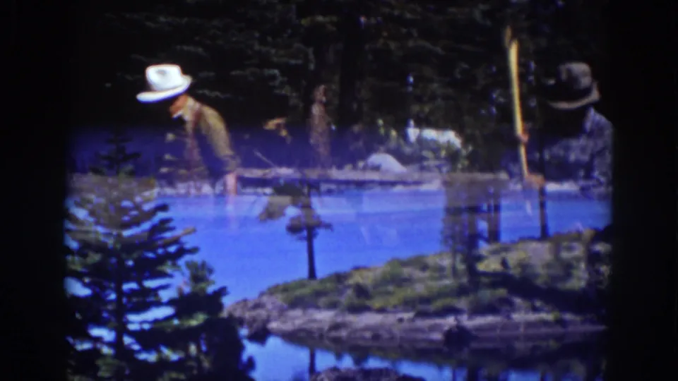 A transitional 8mm frame blends the wood-chopping scene with a Lake Tahoe view of water, shoreline trees, and distant hills.