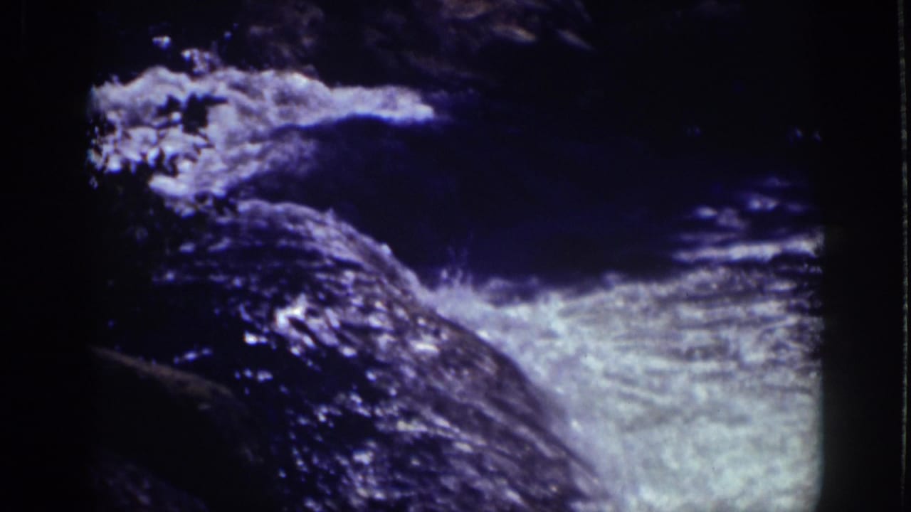 Rushing water spills over dark rocks with white froth and deep blue shadow.