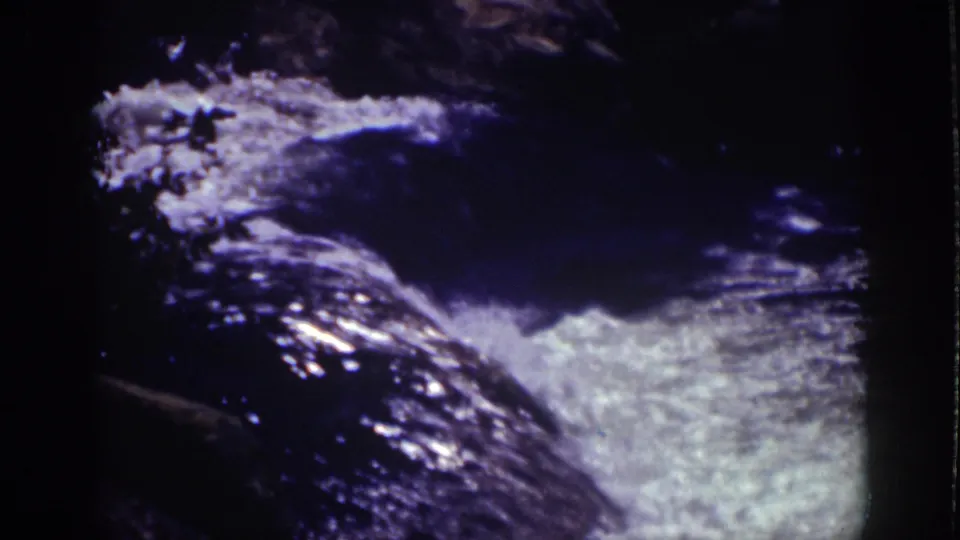 1939 Lake Tahoe 8mm frame with foamy water moving quickly over a sloped rock surface in strong shadow.