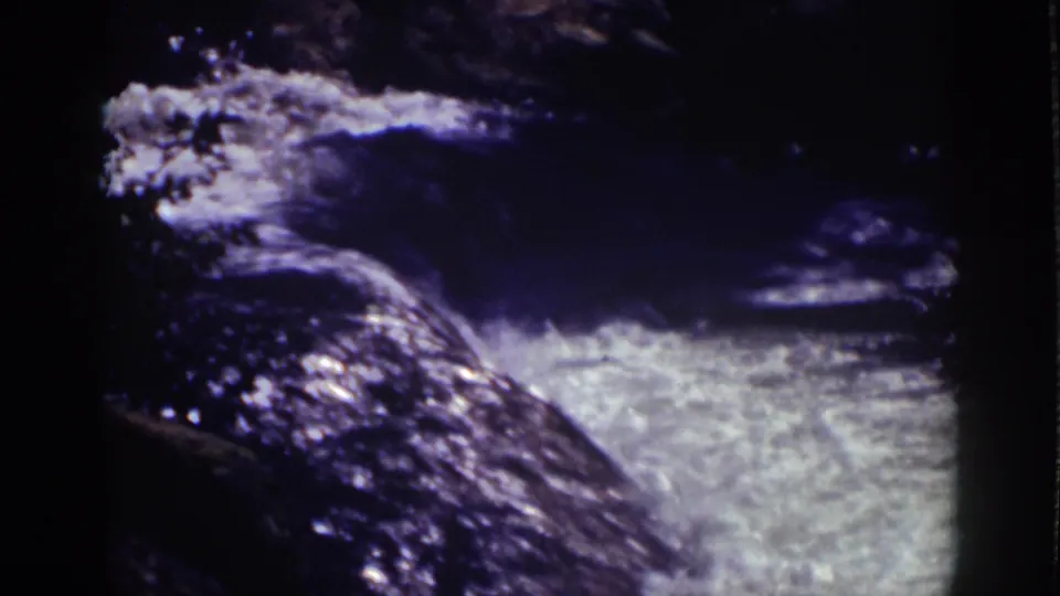 1939 Lake Tahoe 8mm frame showing churning water around dark rocks and bright white foam in the lower frame.