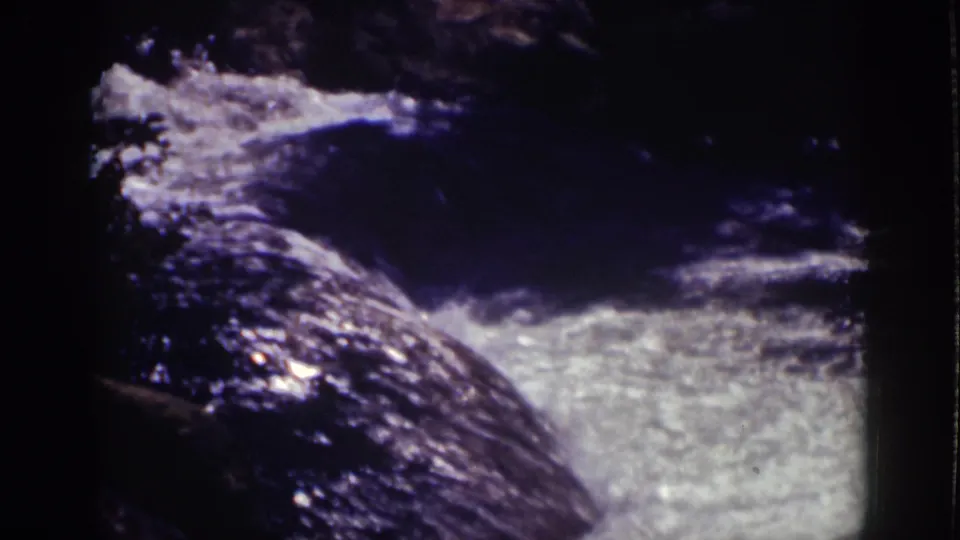 1939 Lake Tahoe 8mm frame of fast water passing a dark rock face into a pale foamy section below.