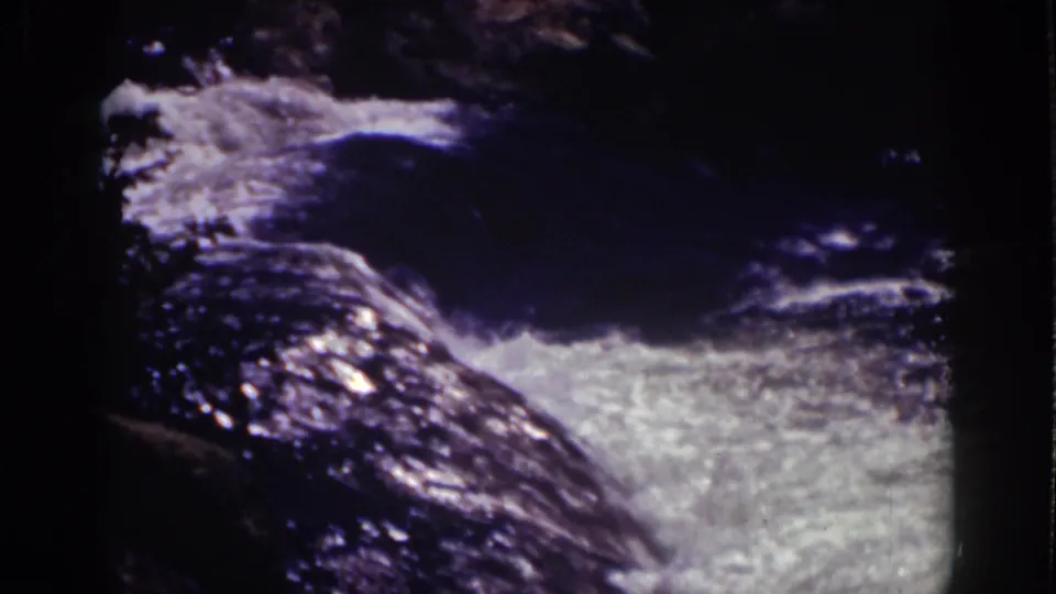 1939 Lake Tahoe home-movie frame showing bright whitewater moving past dark, wet rocks in close view.
