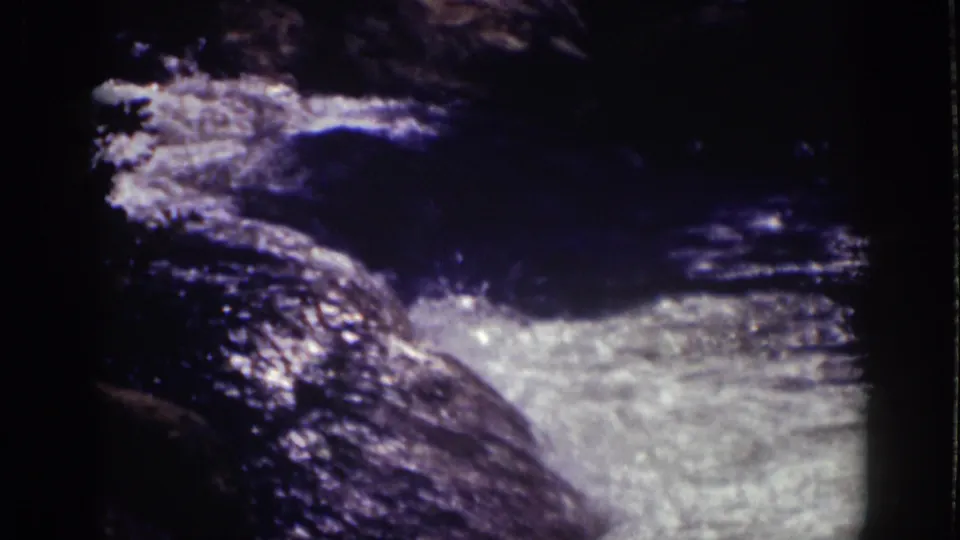 Lake Tahoe stream water appears frothy and sunlit as it moves across dark rocks in 1939 8mm footage.