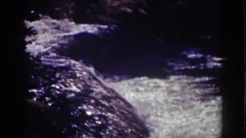 Archival Lake Tahoe frame showing a shaded rocky stream with bright water turbulence in close-up.