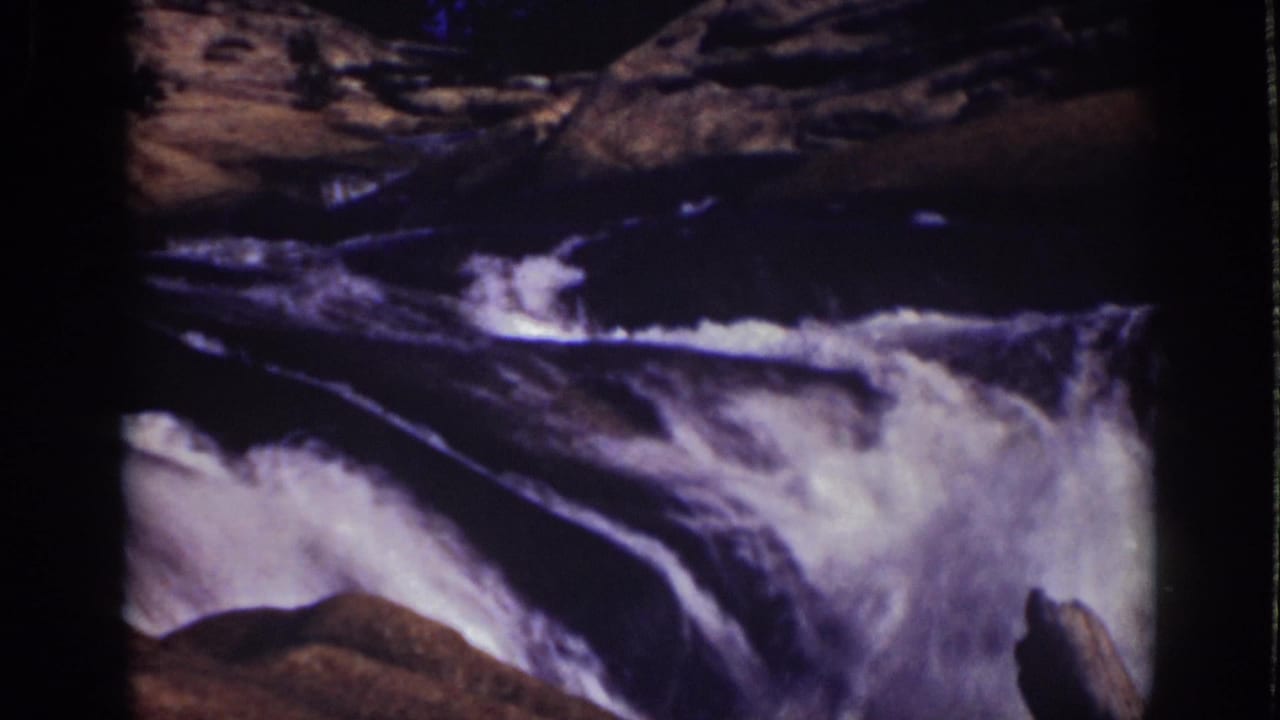 White water rushes through a rocky stream channel with dark film borders.