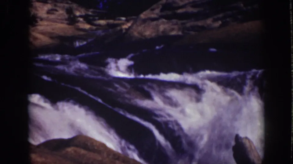 1939 Lake Tahoe home-movie frame showing bright white water flowing between rocks in a narrow mountain stream.