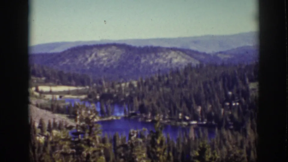 Lake Tahoe, California landscape in 1939 footage, with forested shoreline, blue water, layered ridges, pale sky, and dark 8mm borders.