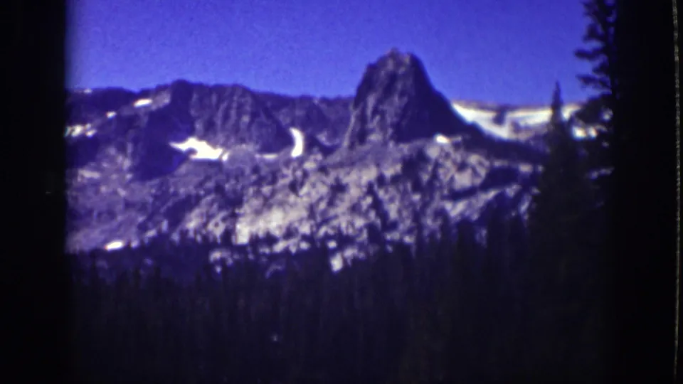 Vintage 8mm Lake Tahoe view of a snow-streaked mountain ridge and shadowed evergreen foreground, dated by metadata to 1939.