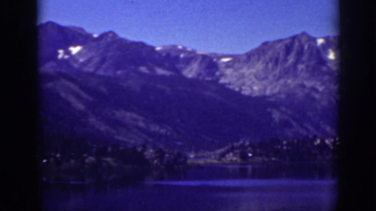 Mountain range above a calm lake, with dark frame edges and blue color cast.