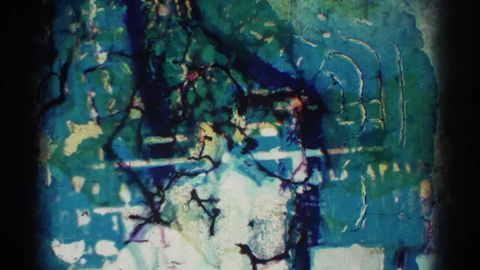 Abstract damaged 8mm film frame with blue-green color shifts, scratches, stains, and darkened borders before the El Monte scene.